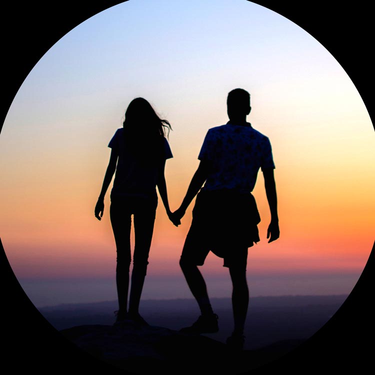 Un homme et une femme se tiennent la main devant un coucher de soleil