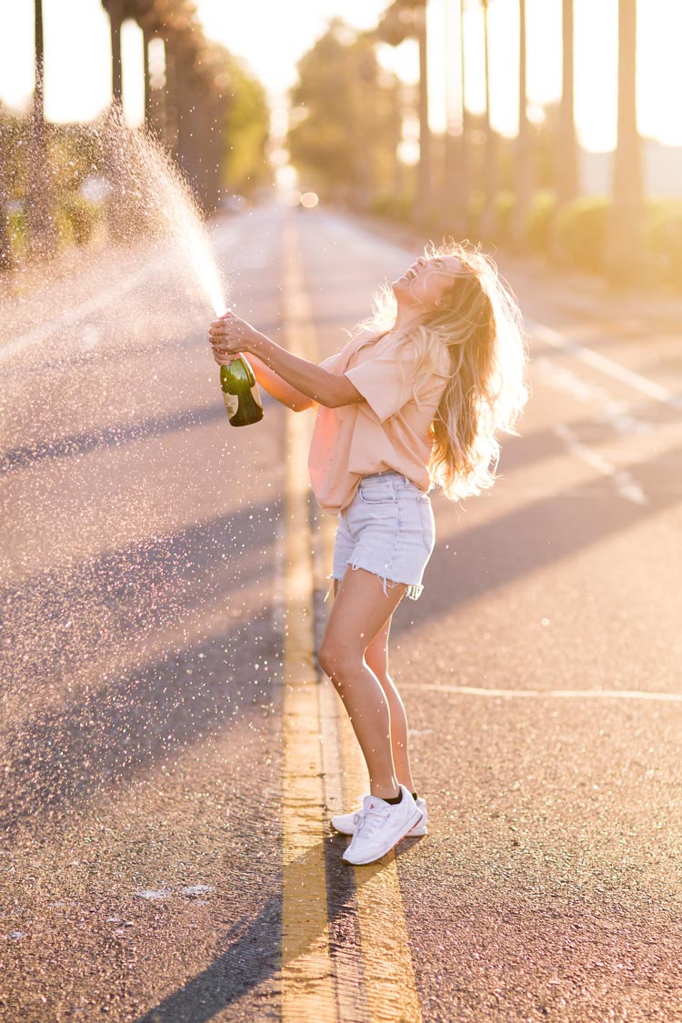 Une jeune fille joyeuse fait gicler une bouteille de champagne